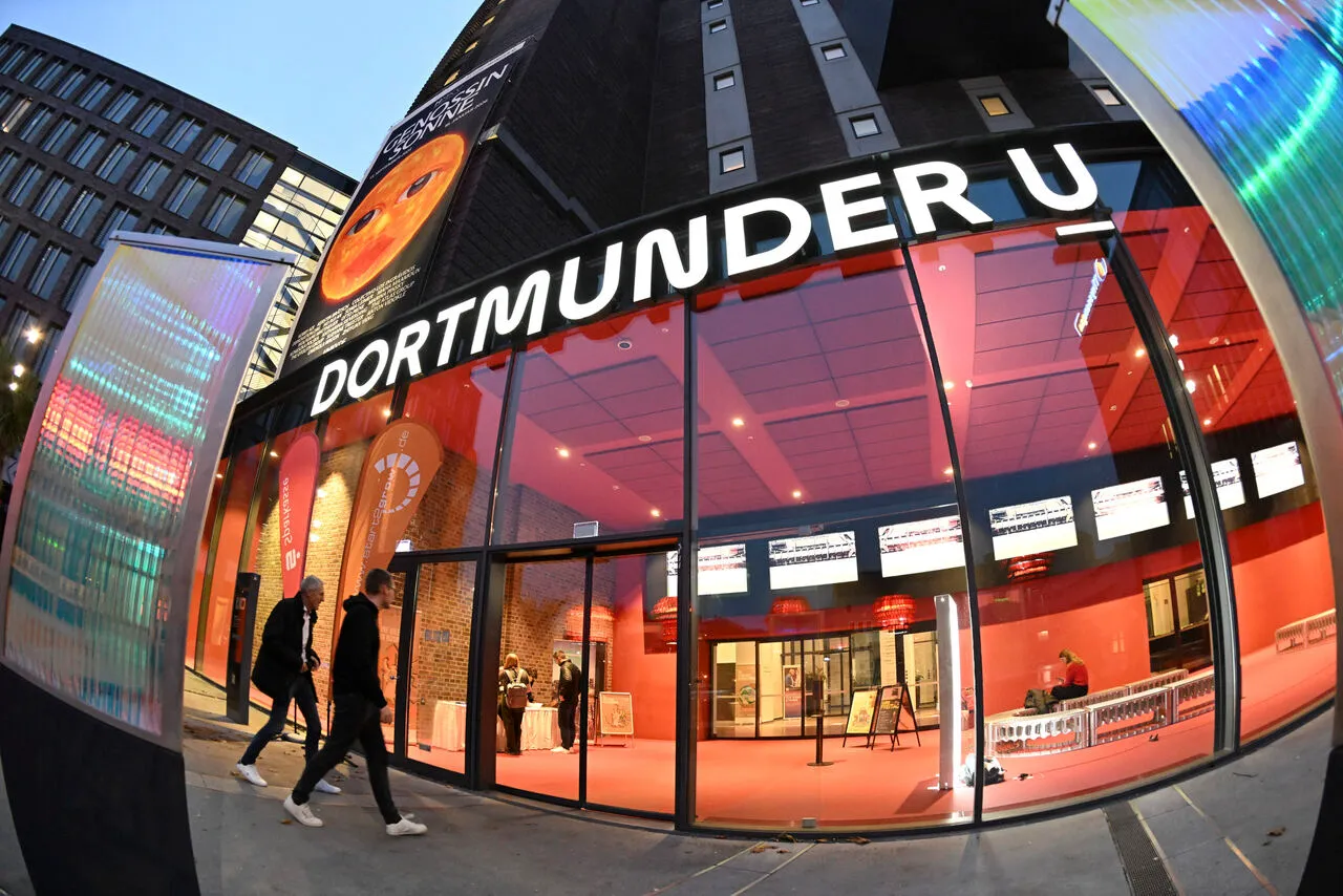 The illuminated glass entrance of Dortmund U at evening during a start2grow event, with start2grow and Sparkasse banners at the doorway.